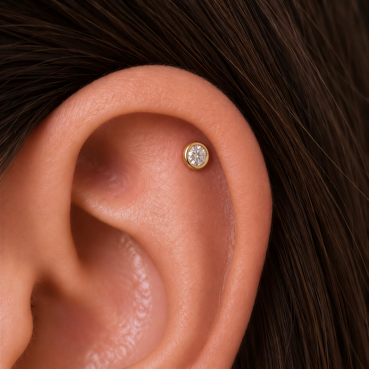 A close-up of an ear with a small diamond earring in the earlobe.