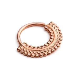 A copper-colored metal ring with a decorative leaf-like design on the surface.