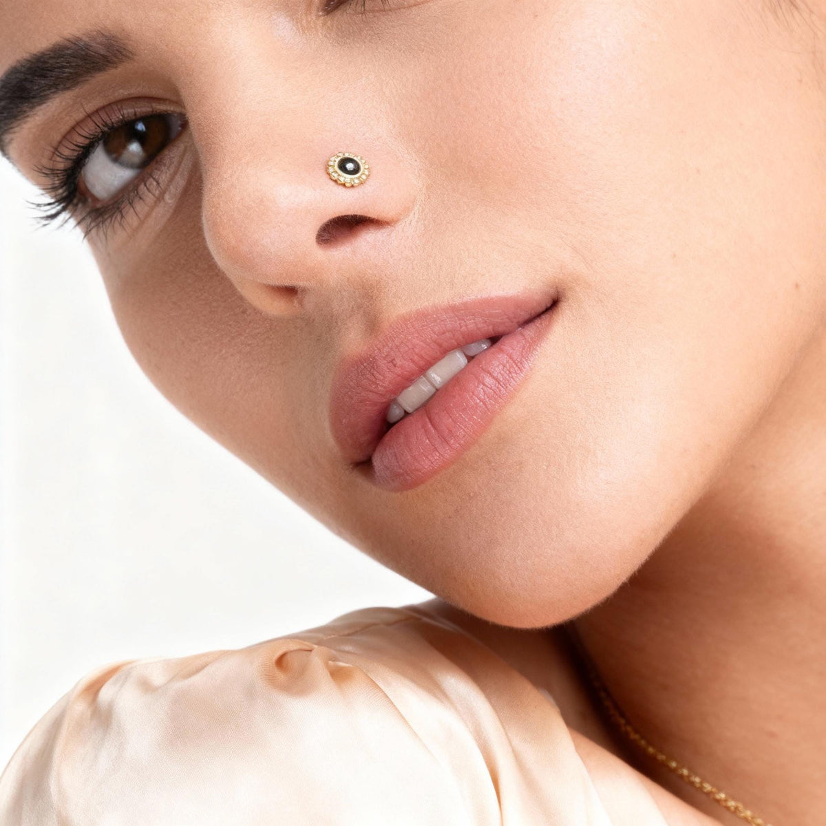 A close-up of a woman's face, focusing on her nose and lips, with a gold nose ring visible.