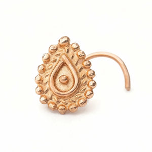 A gold-colored nose ring with an intricate, decorative design.