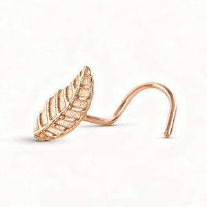 A gold-colored leaf-shaped nose ring is shown against a white background.