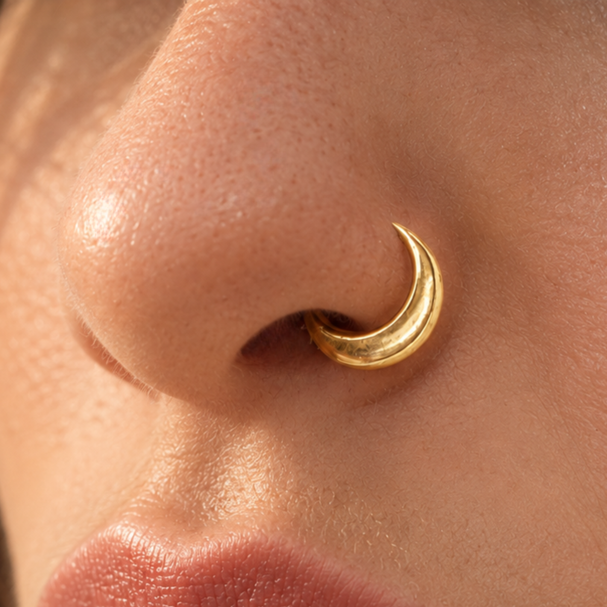 A close-up of a person's nose with a gold hoop earring in their nostril.