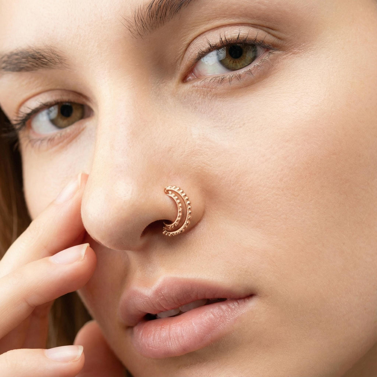 A close-up of a woman's face, focusing on her nose and lips, with a nose ring visible.