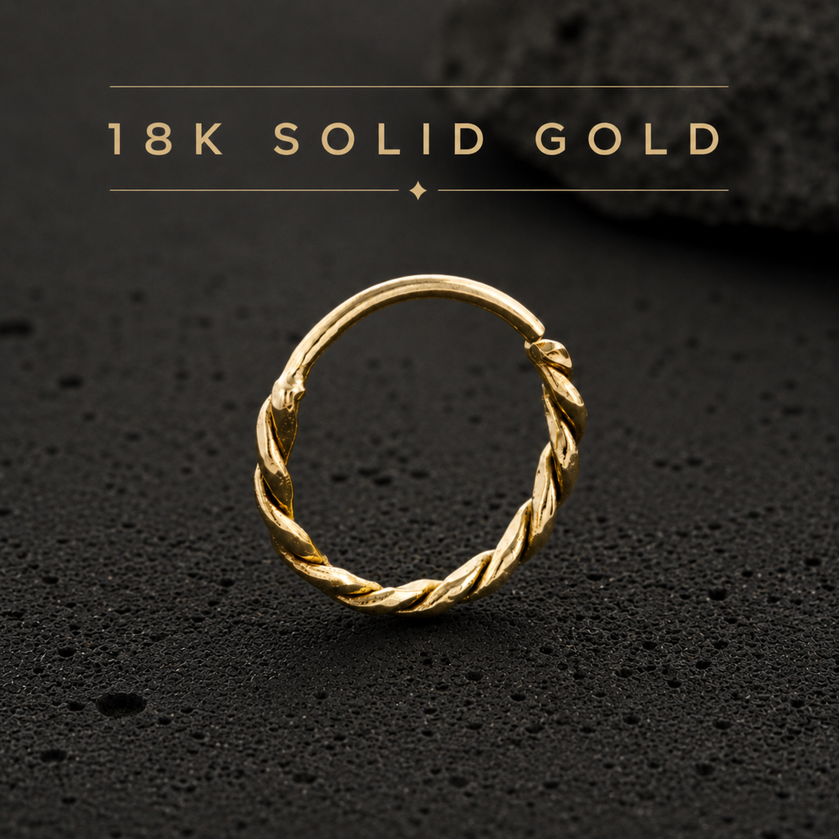 A gold ring with a twisted design is displayed on a black surface.