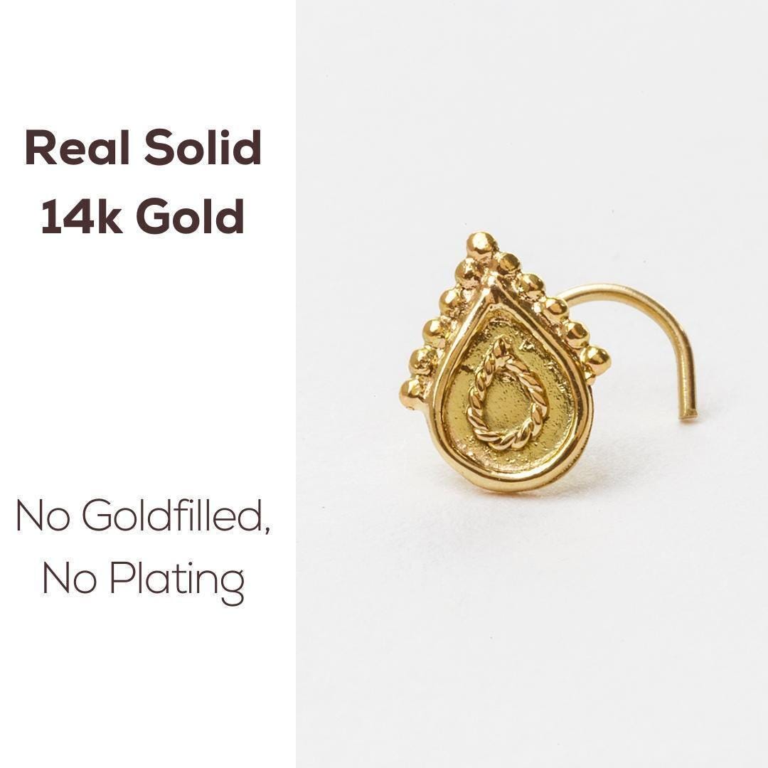 a gold nose ring with a decorative design on the front.