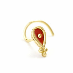 A gold-colored nose ring with a red gemstone in the center.